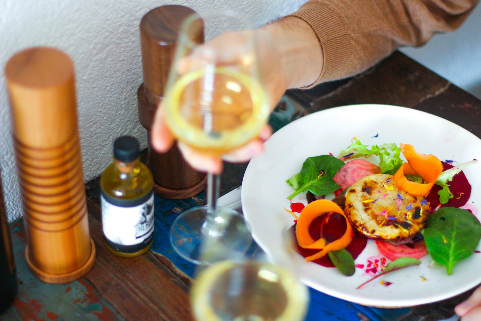 person holding wine glass in front of vegetable salad